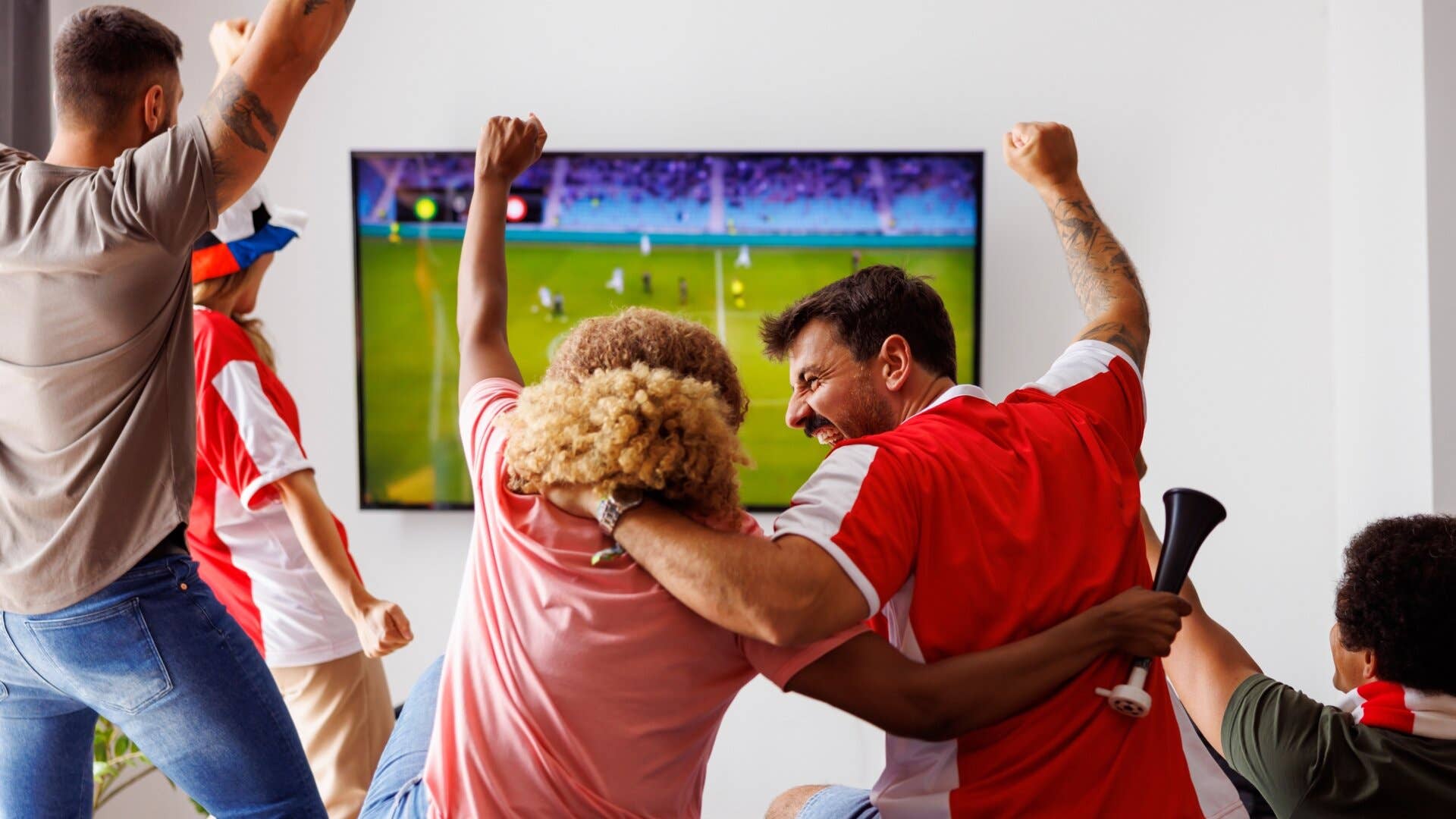 Les gens applaudissent en regardant le sport à la télévision.